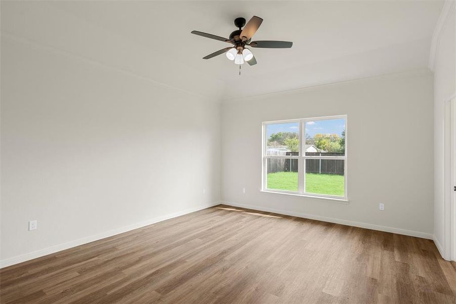 Spare room with light wood-style flooring, a ceiling fan, and ornamental molding Spare room with light wood-style flooring, a ceiling fan, and ornamental molding