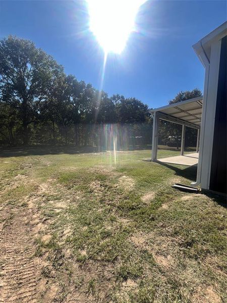 View of green lawn with a patio area View of green lawn with a patio area