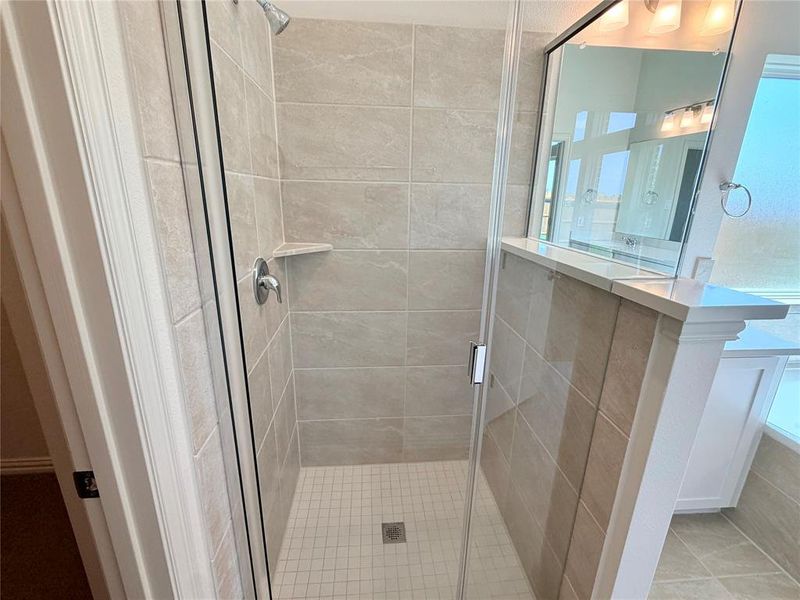 Shower enclosure with clear glass door, chrome fixtures, and a tiled interior