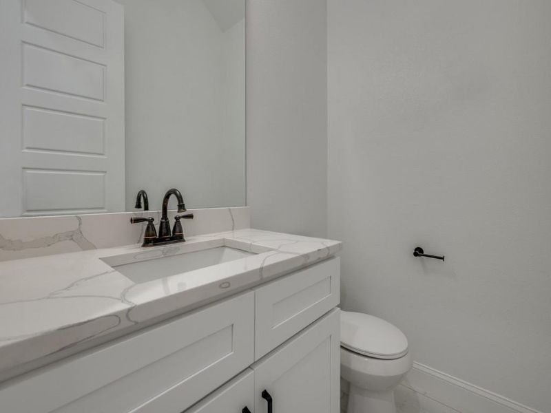 Bathroom with baseboards, vanity, toilet, and marble look tiles