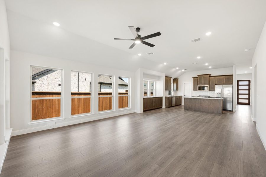 Open living area with hardwood floors and ceiling fan flowing into kitchen with dark wood cabinets and island Open living area with hardwood floors and ceiling fan flowing into kitchen with dark wood cabinets and island