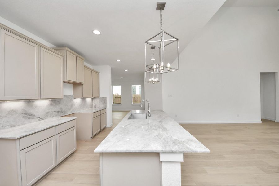 This kitchen is truly a chef's dream! This haven Boasts high ceilings, recessed & pendant lighting, stained wood cabinets, granite countertops, stainless steel appliances, a modern tile backsplash.  All of this overlooks your expansive family room, creating a perfect space for culinary delights and family gatherings. Sample photo of completed home with similar floor plan. Actual colors and selections may vary.
