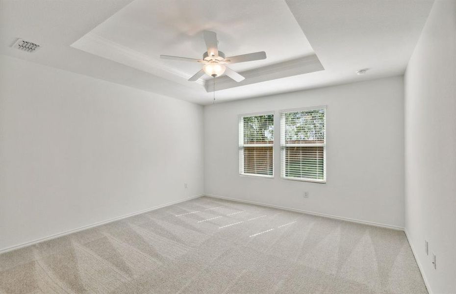 Elegant owner's suite with tray ceiling *real home pictured