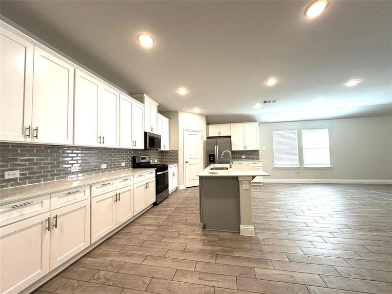 Kitchen featuring white cabinets, a center island with sink, appliances with stainless steel finishes, dark hardwood / wood-style floors, and sink