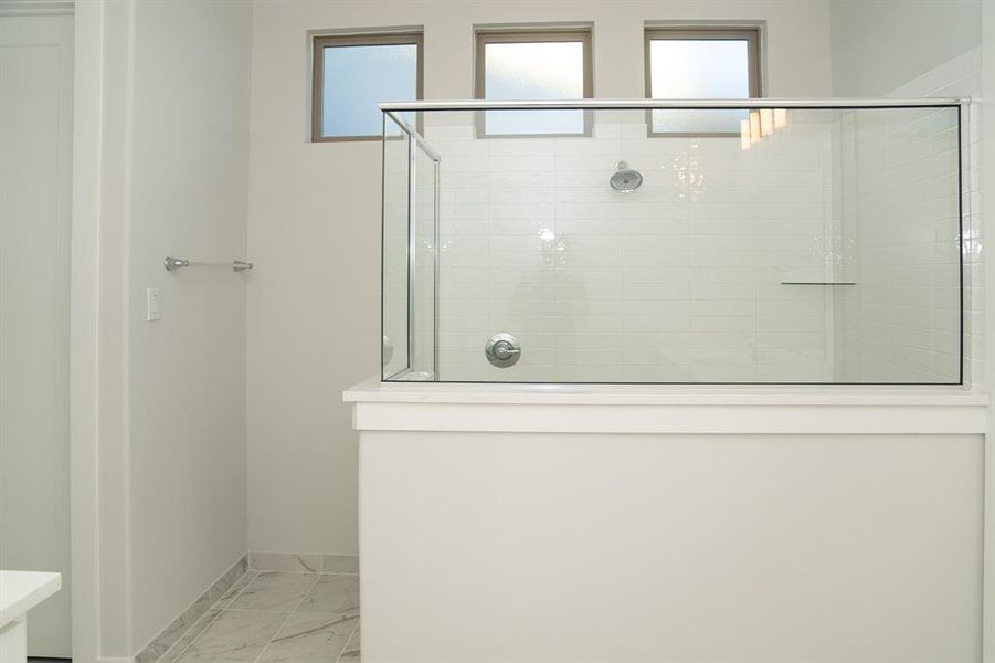 Shower enclosure featuring clear glass panels, a chrome showerhead, and a tiled interior wall with a subway tile pattern Shower enclosure featuring clear glass panels, a chrome showerhead, and a tiled interior wall with a subway tile pattern