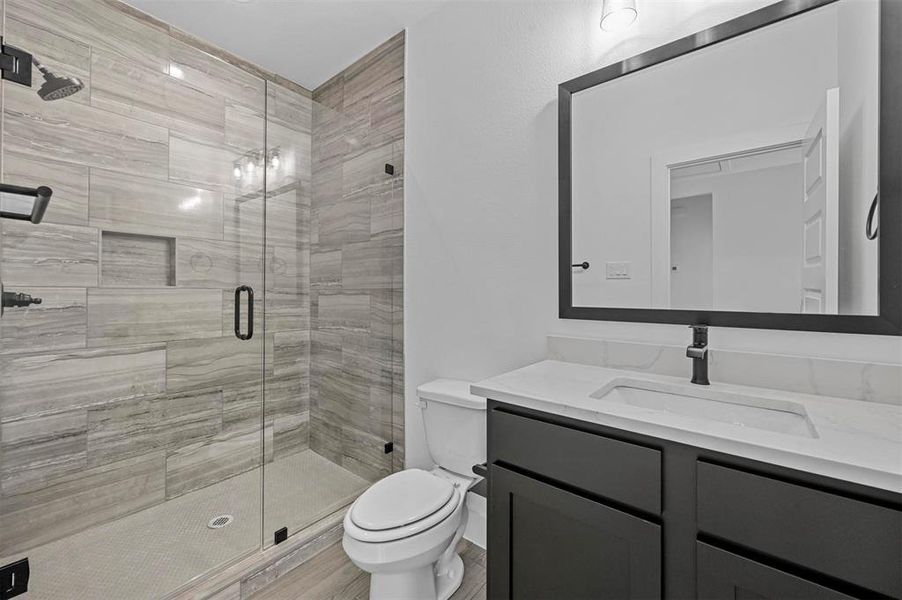 Bathroom featuring a shower with shower door, toilet, and vanity