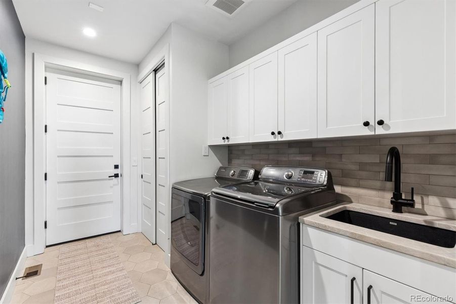Laundry directly off of the garage complete with coat closet, utility sink and more built-in cabinets for added storage Laundry directly off of the garage complete with coat closet, utility sink and more built-in cabinets for added storage