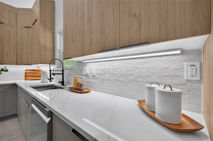 Modern kitchen with sleek quartz countertops, elegant wood cabinetry, and stylish under-cabinet lighting, creating a bright and inviting space for cooking and entertaining.