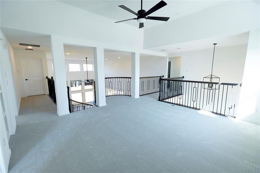 Carpeted empty room featuring ceiling fan and a high ceiling