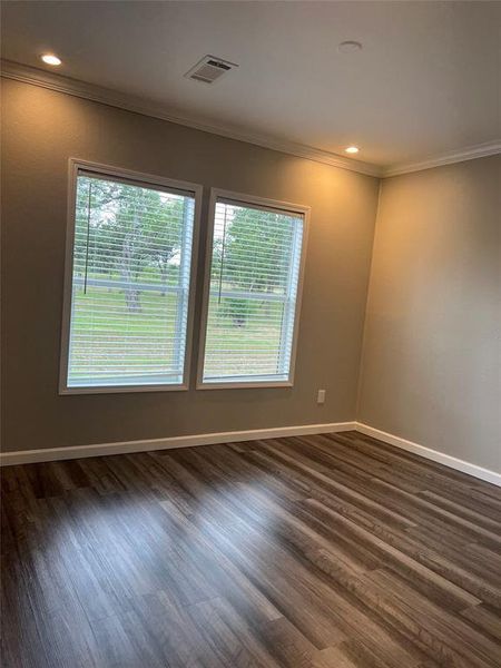 Empty room featuring ornamental molding, dark wood-style floors, and recessed lighting
