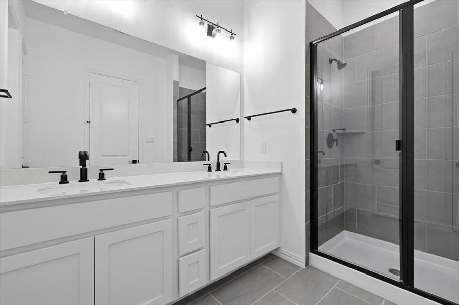 Dual vanities. Quartz countertop, lots of cabinetry and lighting. Separate enclosed shower with sitting area.