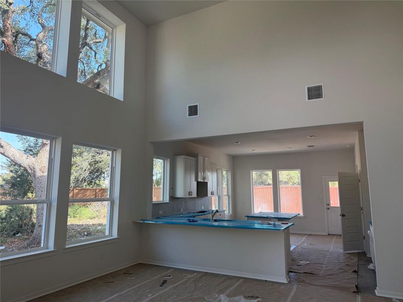 Towering double-height ceilings and massive windows frame leafy views in this open-concept layout.