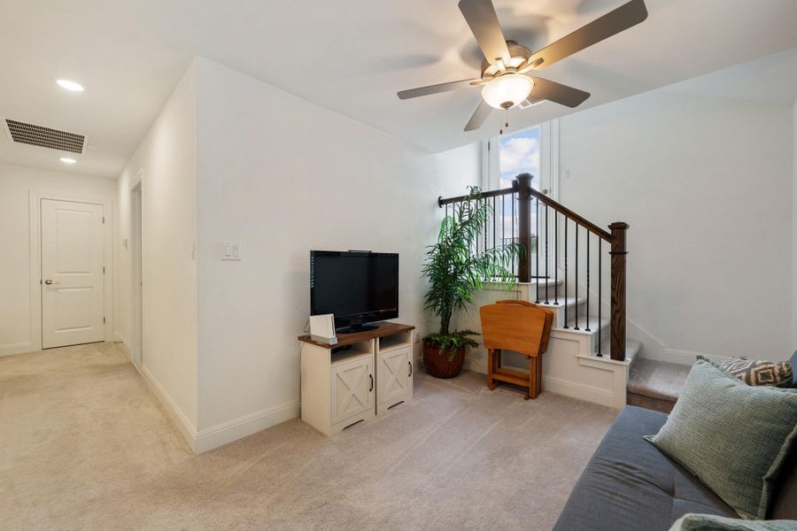 Well-lit living space with a ceiling fan, plush carpeting, and a staircase leading to the upper level. Well-lit living space with a ceiling fan, plush carpeting, and a staircase leading to the upper level.