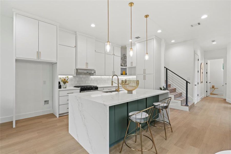 Kitchen with baseboards, stainless steel range with gas stovetop, a sink, and light wood-type flooring