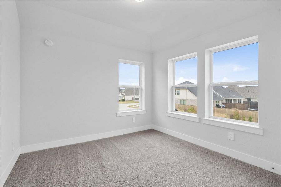 This inviting secondary bedroom combines comfort and modern elegance, featuring a soft neutral color palette, sleek design elements, and abundant natural light streaming through large windows.