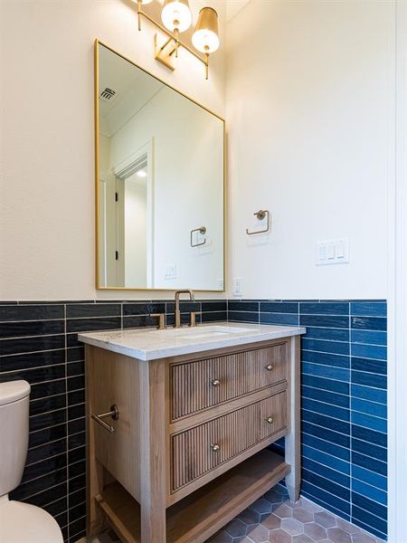 Pool bath is decorated with patterned, textured tile on the walls along with white oak, reeded cabinets.  What a designer touch!