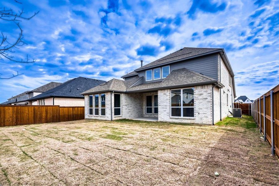 Back of house featuring a patio, brick siding, a fenced backyard, and roof with shingles