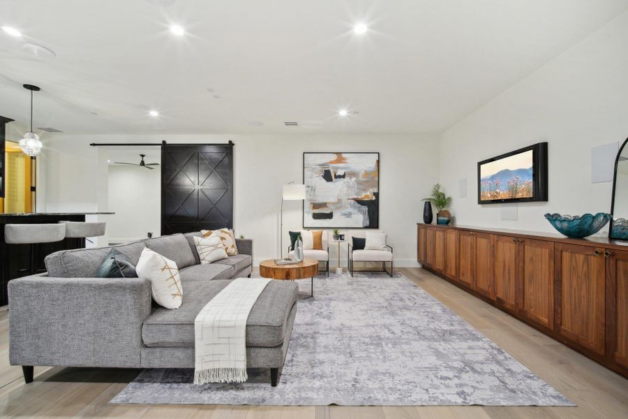 Living area with a barn door, recessed lighting, and light wood-style floors