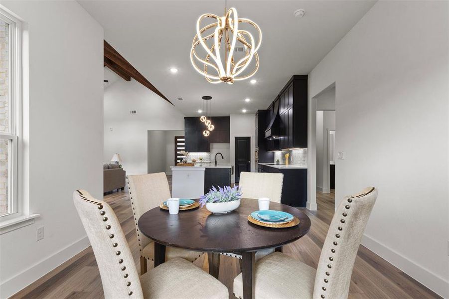 Dining space with a chandelier, wood finished floors, beam ceiling, and recessed lighting
