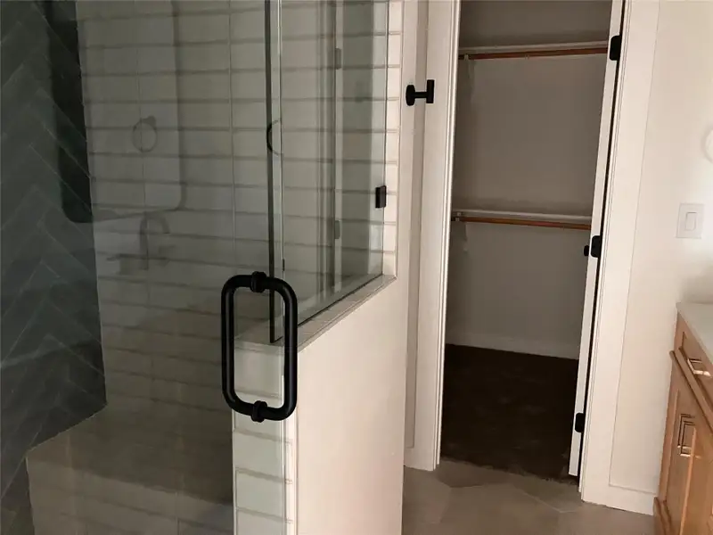 Full bathroom featuring a spacious closet, vanity, a stall shower, and tile patterned flooring