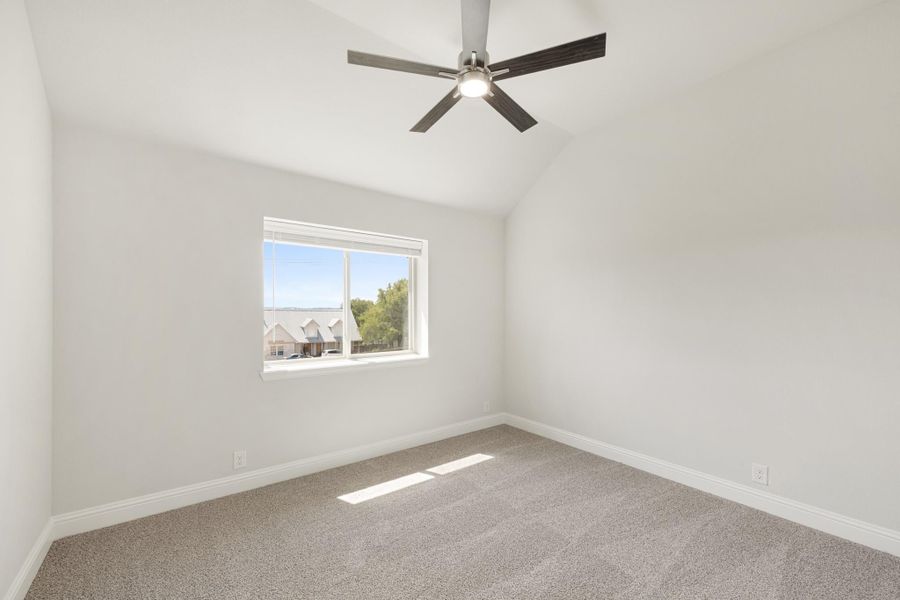 Empty bedroom with vaulted ceiling, ceiling fan, carpet flooring, and single window