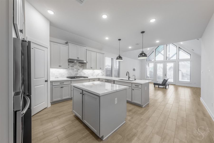 This chef-inspired kitchen boasts sleek cabinetry, beautiful porcelain marble-look countertops, center island, and pendant lighting—all overlooking a dramatic living room with soaring vaulted ceilings and a wall of windows. The open layout creates an elegant flow, perfect for everyday living and entertaining. This chef-inspired kitchen boasts sleek cabinetry, beautiful porcelain marble-look countertops, center island, and pendant lighting—all overlooking a dramatic living room with soaring vaulted ceilings and a wall of windows. The open layout creates an elegant flow, perfect for everyday living and entertaining.