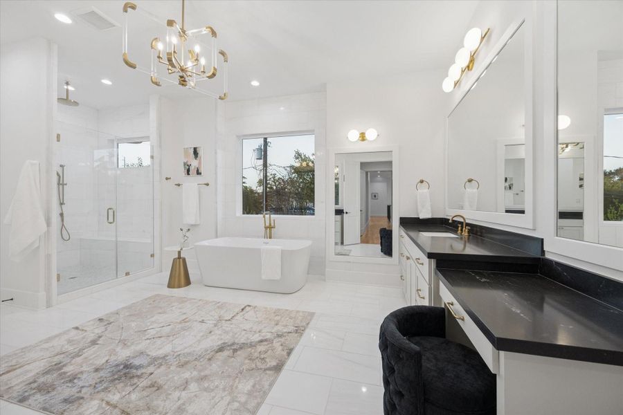 A spa inspired primary bath combines everyday function with a true retreat experience, featuring a freestanding soaking tub, oversized glass enclosed shower, and dual vanities with generous storage. Thoughtful separation of zones allows multiple users to move comfortably through morning routines while designer lighting, stone surfaces, and expansive windows keep the space bright and serene. A spa inspired primary bath combines everyday function with a true retreat experience, featuring a freestanding soaking tub, oversized glass enclosed shower, and dual vanities with generous storage. Thoughtful separation of zones allows multiple users to move comfortably through morning routines while designer lighting, stone surfaces, and expansive windows keep the space bright and serene.