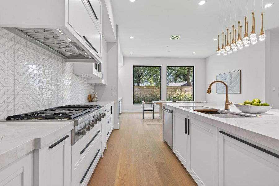 Gourmet kitchen with designer pendant lighting and top-of-the-line stainless steel appliances.