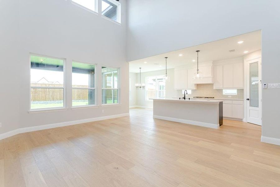 Kitchen with white cabinets, light hardwood / wood-style floors, hanging light fixtures, and tasteful backsplash