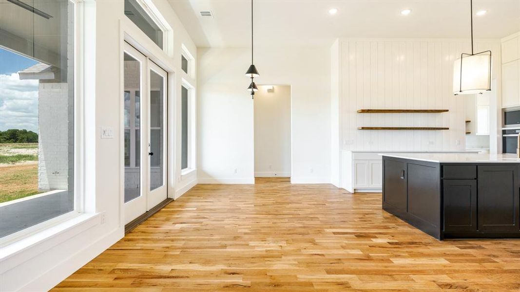 Kitchen with stainless steel appliances, decorative light fixtures, light wood-type flooring, and white cabinets