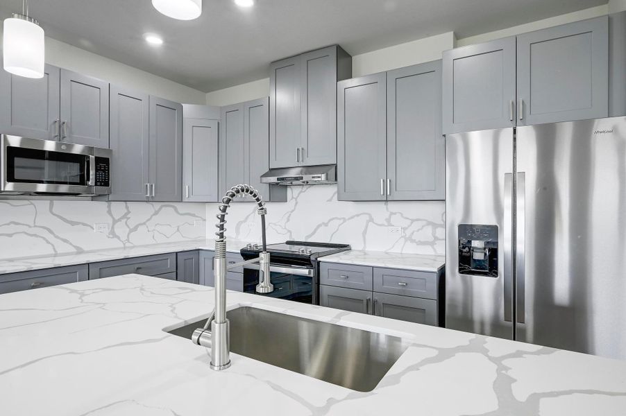 Kitchen featuring appliances with stainless steel finishes, gray cabinets, under cabinet range hood, and recessed lighting