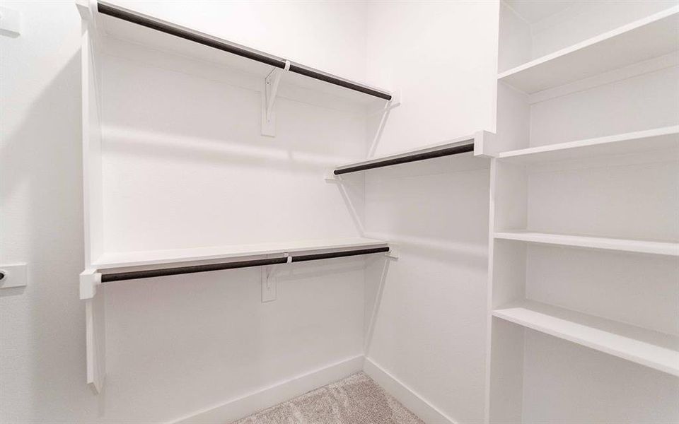 Organized closet featuring multiple white shelving units and dark-finish hanging rods