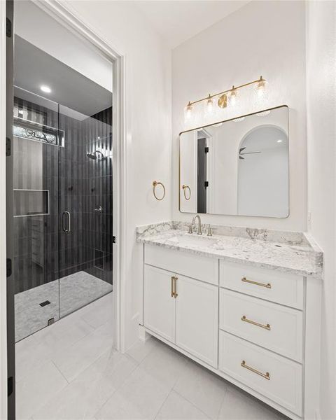 Bathroom featuring a white vanity with gold-tone hardware, a rectangular mirror, and a linear light fixture
