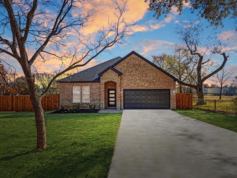 View of front facade with brick siding, driveway, an attached garage, and a shingled roof