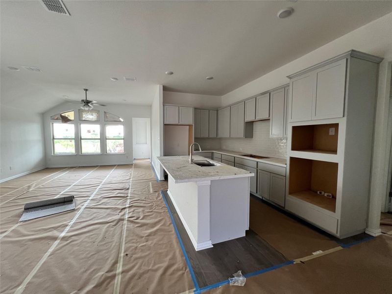 Kitchen with gray cabinetry, an island with sink, ceiling fan, decorative backsplash, and lofted ceiling Kitchen with gray cabinetry, an island with sink, ceiling fan, decorative backsplash, and lofted ceiling