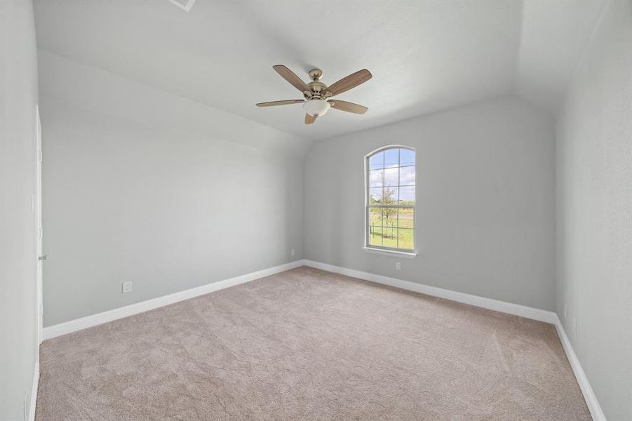 Carpeted empty room with lofted ceiling and ceiling fan