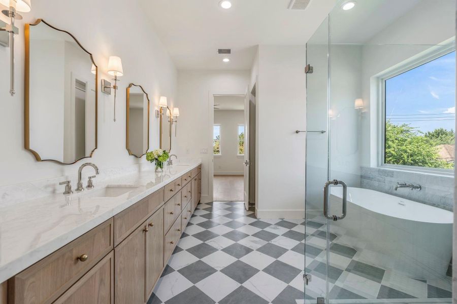 Luxurious primary bathroom featuring dual vanities, a soaking tub, and a separate walk-in shower.