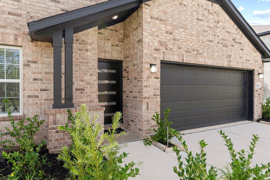A closer look at the inviting entryway shows off a perfect mix of classic brick and stylish dark trim. The covered front porch adds charm and functionality, offering a cozy spot to greet guests or enjoy the fresh air. The modern front door adds just the right touch of sophistication, setting the tone for the home’s bright and contemporary interior.