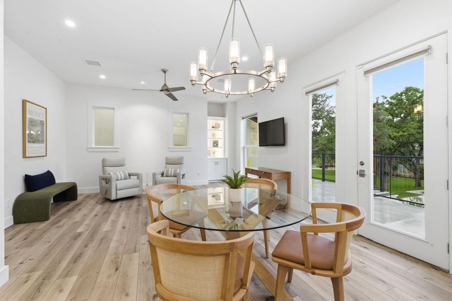 Dining area featuring light wood-style floors, suspended lighting, and a ceiling fan