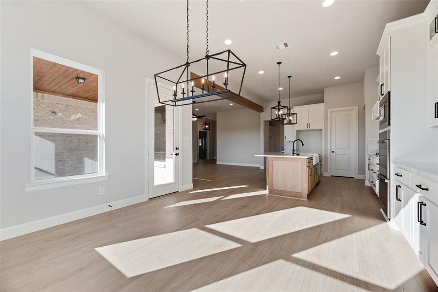 Kitchen featuring open floor plan, a kitchen island with sink, white cabinetry, recessed lighting, and a chandelier Kitchen featuring open floor plan, a kitchen island with sink, white cabinetry, recessed lighting, and a chandelier