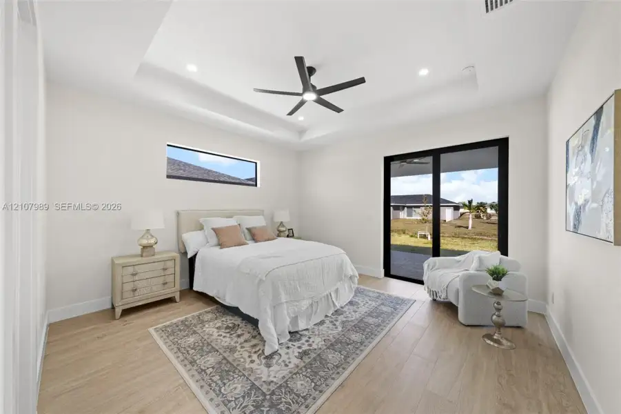 Tray ceiling with recessed lighting, wood-finish flooring, matte black ceiling fan, horizontal clerestory window, and black-framed sliding glass doors Tray ceiling with recessed lighting, wood-finish flooring, matte black ceiling fan, horizontal clerestory window, and black-framed sliding glass doors