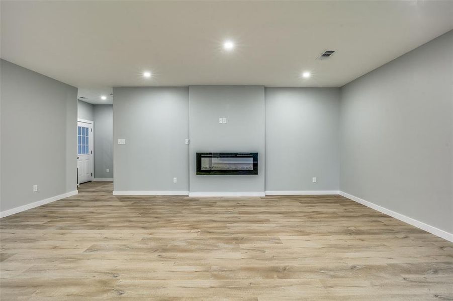 Unfurnished living room featuring heating unit and light hardwood / wood-style flooring