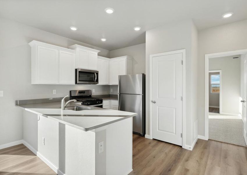 The kitchen has stainless steel appliances and plank flooring.