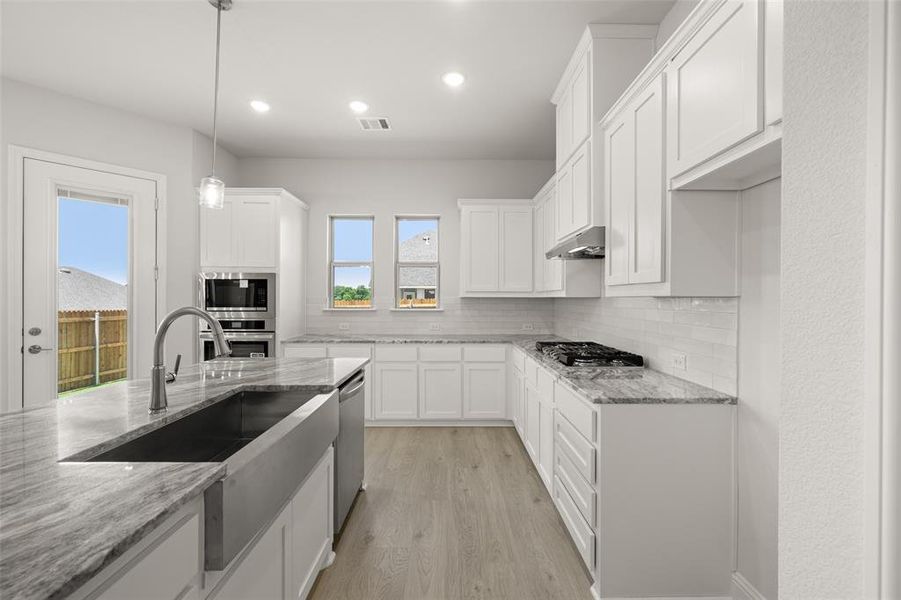 Kitchen featuring stainless steel appliances, backsplash, white cabinetry, and recessed lighting Kitchen featuring stainless steel appliances, backsplash, white cabinetry, and recessed lighting