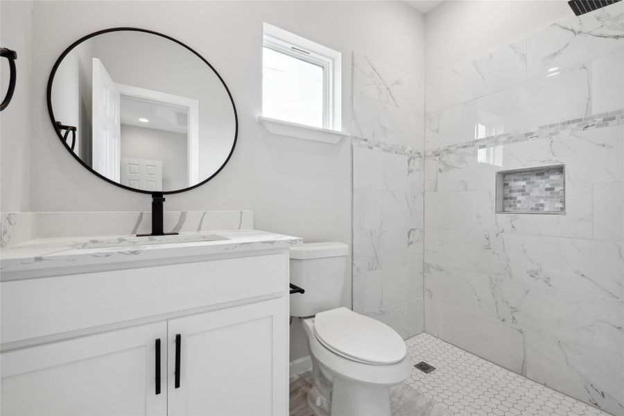 Full bathroom featuring toilet, vanity, and a tile shower Full bathroom featuring toilet, vanity, and a tile shower