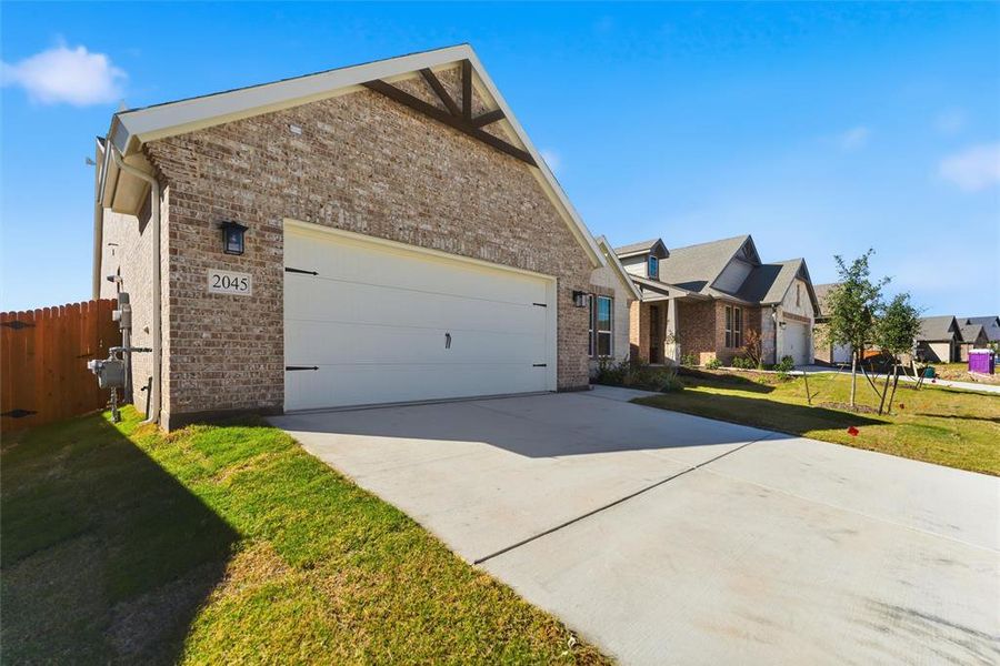 View of front of house with concrete driveway, brick siding, and an attached garage