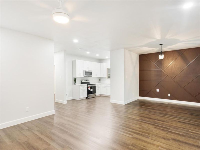 Unfurnished living room with recessed lighting, an accent wall, light wood-style flooring, wood walls, and a barn door