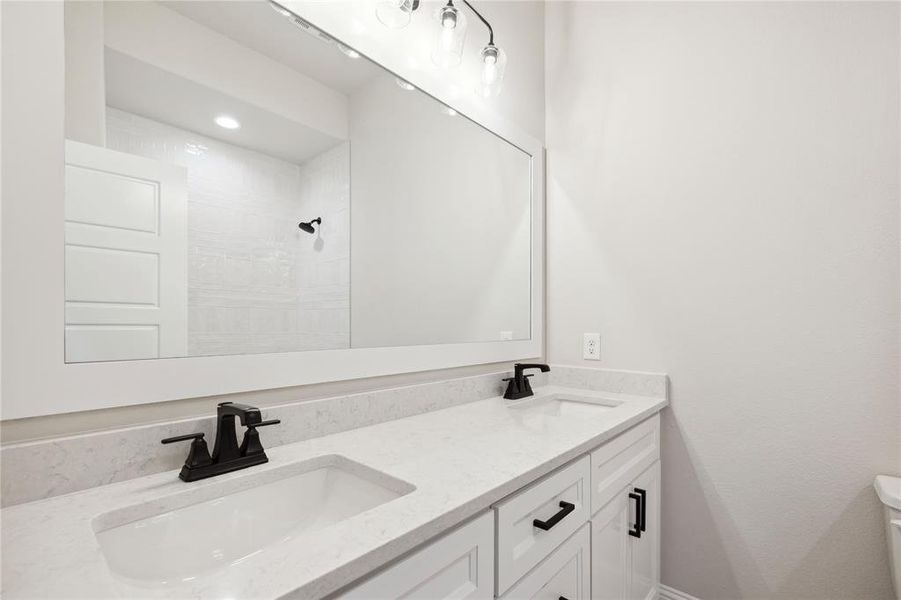 Bathroom featuring a shower, vanity, and toilet