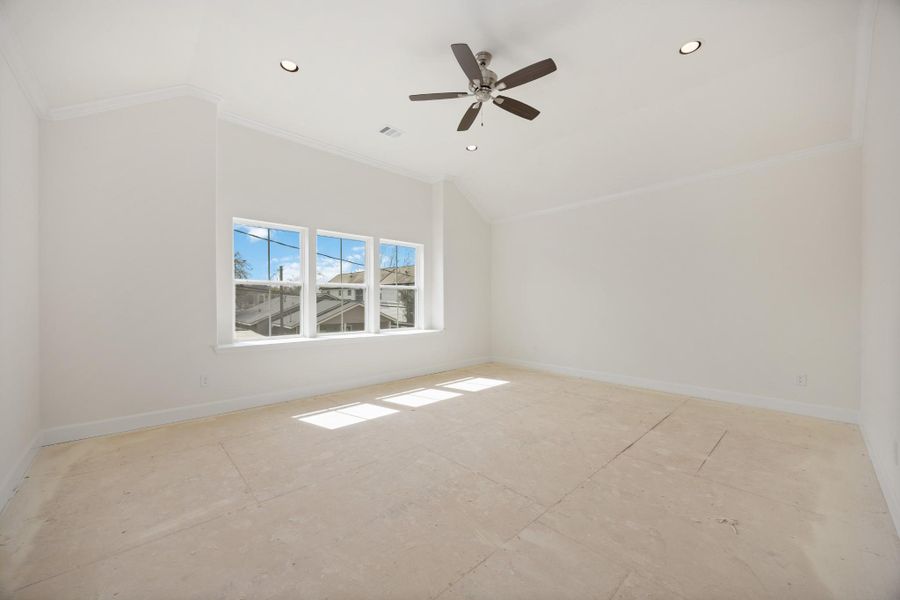 Step into a primary suite that lives like a luxury retreat—soaring ceilings, soft carpet underfoot, and a wall of windows bringing the outside in.