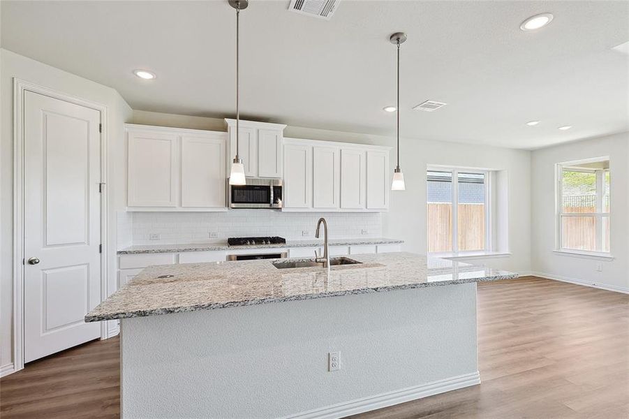 Kitchen featuring sink, white cabinetry, hanging light fixtures, and light hardwood / wood-style flooring